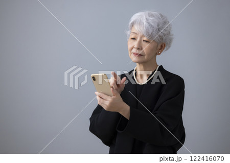 喪服　スマホを見ているシニア女性 122416070