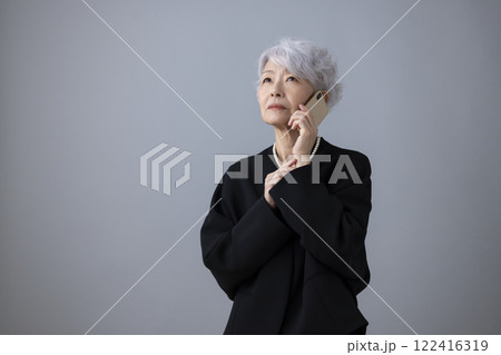喪服　スマホで電話をかけているシニア女性 122416319