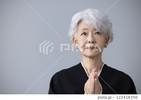 喪服を着て手を合わせているシニア女性 122416350