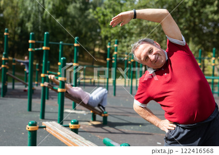 Elderly man doing gymnastics on an outdoor sports ground 122416568