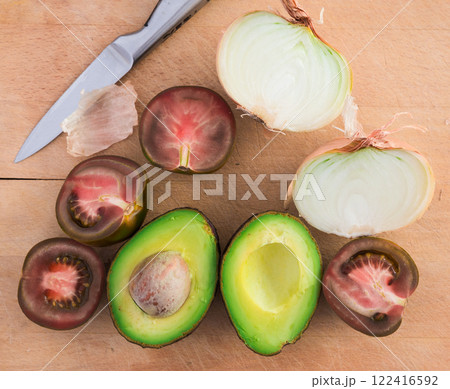 Vegetables black tomatoes, avocado and onions on wooden board 122416592
