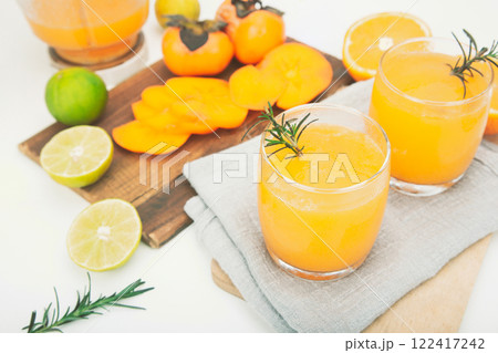 persimmon juice in a glass And there are orange slices and a blender all around. persimmon juice in a glass And there are orange slices and a blender all around. 122417242