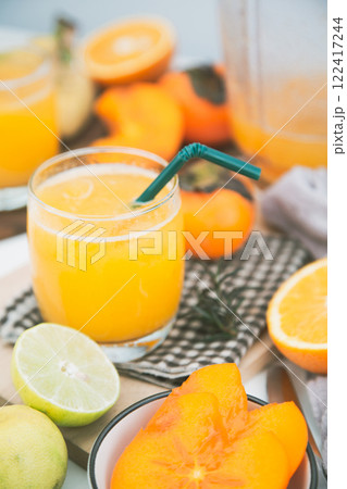 persimmon juice in a glass And there are orange slices and a blender all around. persimmon juice in a glass And there are orange slices and a blender all around. 122417244