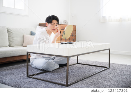 鏡を見て下地やファンデーションなどを塗る若い男性の美容やビューティーイメージ　俯瞰 122417891