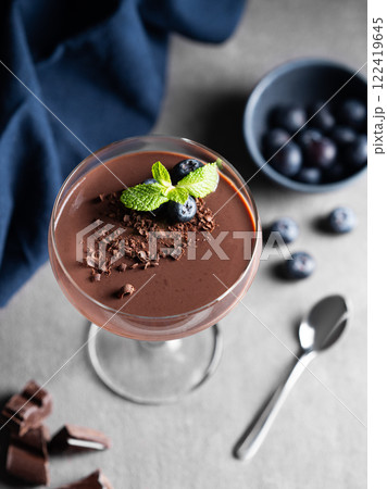 Chocolate pudding in a tall glass with mint and fresh blueberry on a dark background 122419645