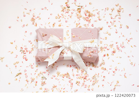 Sustainable wrapped present and dried petals confetti. Zero waste holiday background. 122420073