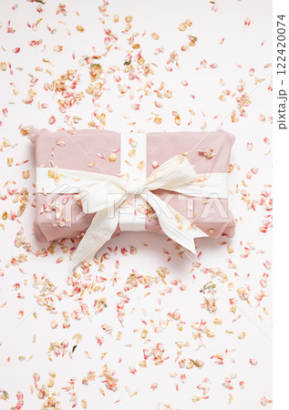 Sustainable wrapped present and dried petals confetti. Zero waste holiday background. 122420074