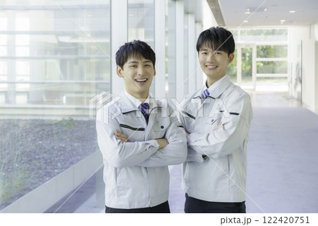 作業着を着て腕組みをして通路に立つ若い男性2人のポートレート 122420751