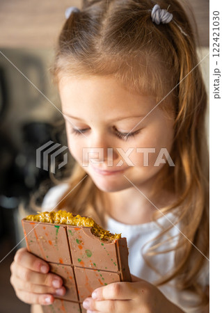 Little girl eating Dubai chocolate with pistachio paste and kataifi dough. Confectionery handmade sweets at home in the kitchen. Little girl eating Dubai chocolate with pistachio paste and kataifi dough. Confectionery handmade sweets at home in the kitchen. 122421030