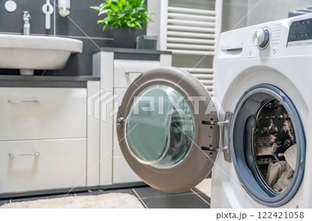 Washing machine with open door in modern, white and grey bathroom in home Washing machine with open door in modern, white and grey bathroom in home 122421058