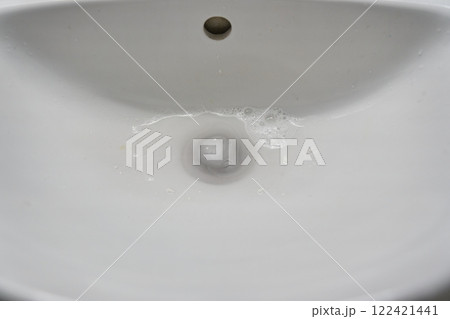Top view of a ceramic bathroom sink with water going down the drain. With space to copy. High quality photo 122421441