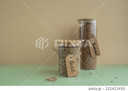 Raw buckwheat porridge and green lentil in sustainable natural packaging. Refillable systems. Gluten free cereals. Health gut benefits. Concept of alternative whole spelt grain ingredient. Vegetarian Raw buckwheat porridge and green lentil in sustainable natural packaging. Refillable systems. Gluten free cereals. Health gut benefits. Concept of alternative whole spelt grain ingredient. Vegetarian 122421450