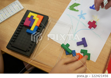 A plastic tetris game. Leisure time for children on vacation. An unrecognizable child is playing a plastic-based puzzle game. With space to copy. High quality photo 122421456