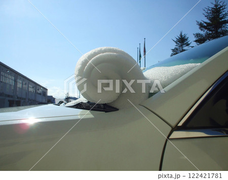 乗用車の窓に積もった雪が晴天の気温上昇で徐々に滑り落ちながら渦巻き状に丸まった珍しい自然現象 122421781