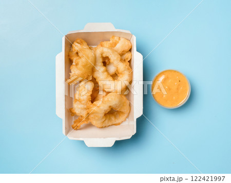 Oven baked breaded calamari or Kara-age squid rings served with sweet and sour sauce. Top view or flat lay. Isolated on blue solid background. Crispy Delight Tangy, Tempting. The Perfect Karaage Squid Oven baked breaded calamari or Kara-age squid rings served with sweet and sour sauce. Top view or flat lay. Isolated on blue solid background. Crispy Delight Tangy, Tempting. The Perfect Karaage Squid 122421997