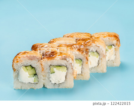 Studio photography of Philadelphia Roll of velvety cream cheese and cucumber wrapped in perfect seasoned sushi rice and fresh unagi smoked eel. Isolated on solid light blue background 122422015