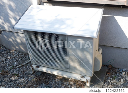 庭に設置された古いタイプのエアコンの室外機 122422561