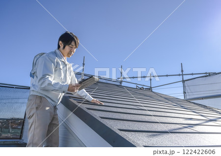 戸建て家屋の屋根修繕工事進行状況を確認する男性 戸建て家屋の屋根修繕工事進行状況を確認する男性 122422606