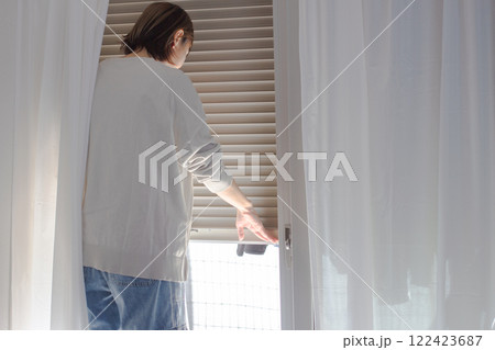 窓のシャッターを開閉する女性のイメージ 窓のシャッターを開閉する女性のイメージ 122423687