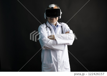 Telemedicine concept, old Asian doctor in lab uniform wearing VR glasses and operating medical task standing on black background. Telemedicine concept, old Asian doctor in lab uniform wearing VR glasses and operating medical task standing on black background. 122426157
