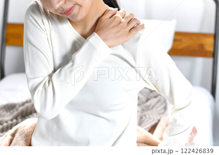 ベッドの上で肩こりに悩むアジア人女性 ベッドの上で肩こりに悩むアジア人女性 122426839