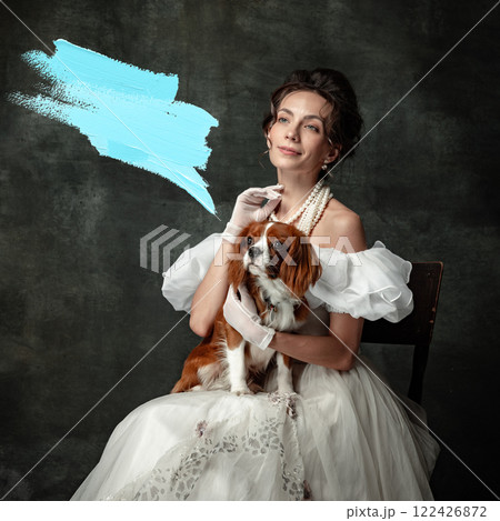 Vintage portrait of young elegant woman in image of medieval princess in renaissance style dress sitting with cute pet with blue abstract speech bubble. 122426872