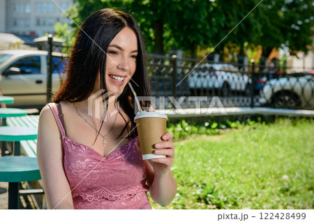 Young woman drinking coffe outdoor in a sunny day. Female with a paper cup of coffee in hand. Young woman drinking coffe outdoor in a sunny day. Female with a paper cup of coffee in hand. 122428499