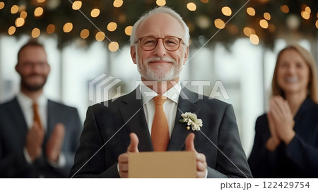 Retiree giving a farewell speech while colleagues applaud in a well-decorated office space 122429754
