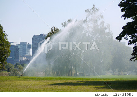 Irrigation system on the Danube Island Donauinsel in Vienna. Watering of grass lawn and trees in park on a hot summer day. Drought protection farming concept Irrigation system on the Danube Island Donauinsel in Vienna. Watering of grass lawn and trees in park on a hot summer day. Drought protection farming concept 122431090