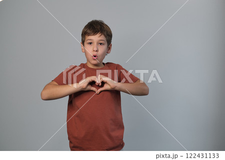 Child shows a heart sign, cheerful and loving. Captures the open-heartedness of youth and the simple ways they express emotions. Child shows a heart sign, cheerful and loving. Captures the open-heartedness of youth and the simple ways they express emotions. 122431133