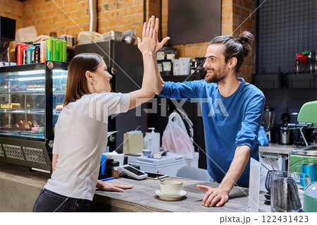 Young man cafe worker shaking hands with woman client customer colleague in coffee shop 122431423