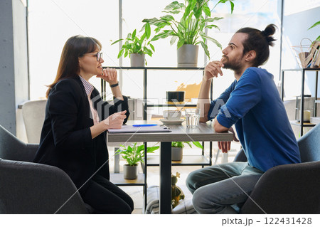 Middle aged female mental health specialist, insurance agent working with young male Middle aged female mental health specialist, insurance agent working with young male 122431428