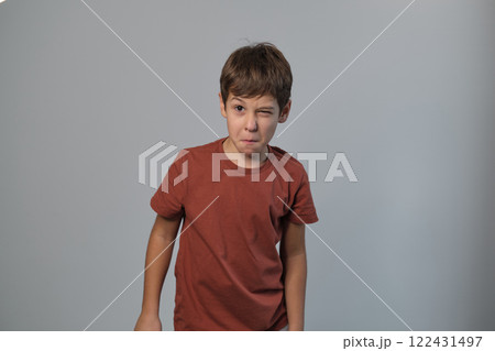 A frustrated young boy with attitude is positioned in front of a plain gray backdrop 122431497