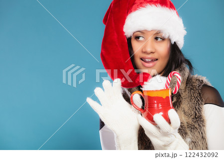 Winter girl santa helper hat holds red mug 122432092