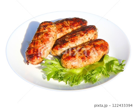 Grilled meat sausages and green salad leaves on a plate 122433394