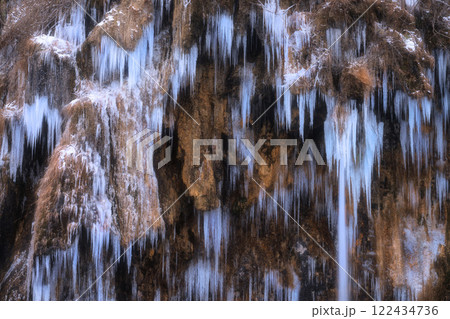Winter frozen waterfall with icicles on moss-covered rocks 122434736
