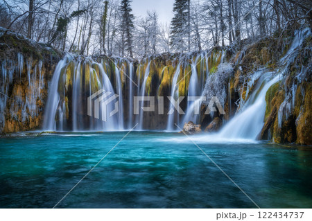 Winter waterfall, lake, frozen trees with icicles in cold evening 122434737