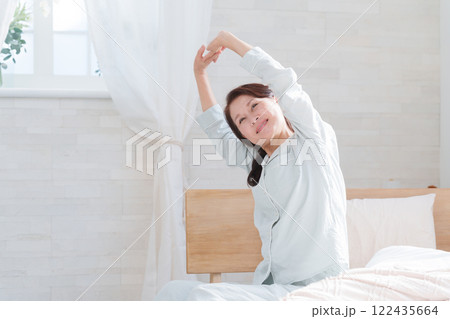 ベッドの上でストレッチするシニア女性 122435664