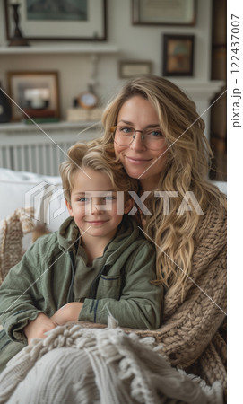 A woman and a young boy are sitting on a couch, with the woman wearing glasses 122437007
