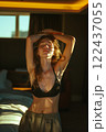 A woman is standing in a bedroom with her arms raised 122437055