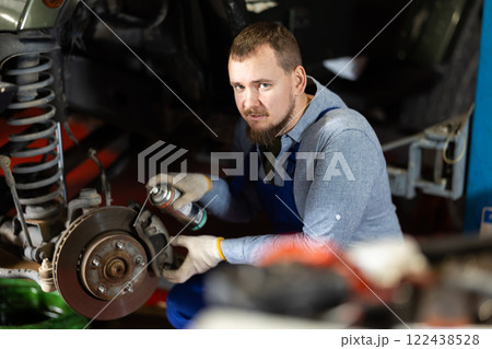 Mechanic applying anti-rust liquid to bolts on car wheel hub 122438528