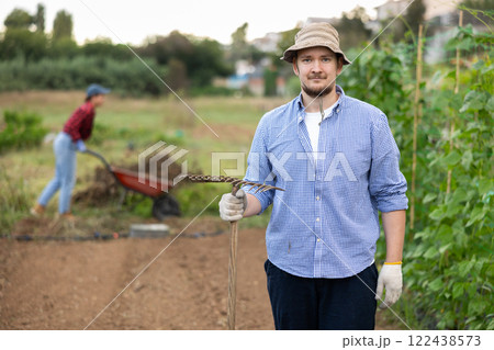 Portrait of man holding a rake in farmer field 122438573