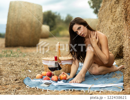 Nude woman sitting during picnic in field Nude woman sitting during picnic in field 122438621