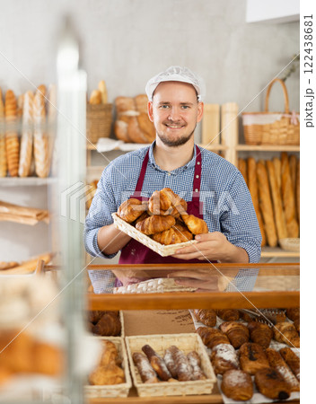 Selling fresh croissants in bakery - Baker places hot croissants on display Selling fresh croissants in bakery - Baker places hot croissants on display 122438681