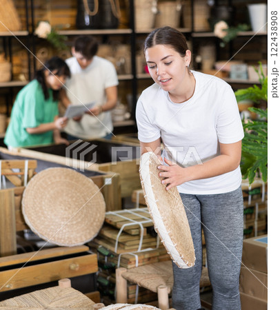 woman examines round pillow made of wicker for garden furniture before buying 122438908