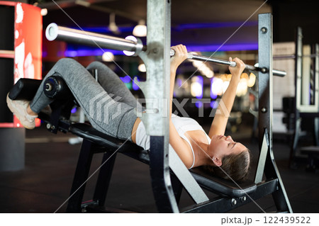 Young woman exercising on barbell machine Young woman exercising on barbell machine 122439522