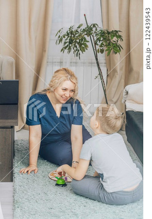 Child engaged in a developmental board game with a therapist on the floor, representing early childhood education and cognitive skill improvement, concept of learning through play Child engaged in a developmental board game with a therapist on the floor, representing early childhood education and cognitive skill improvement, concept of learning through play 122439543