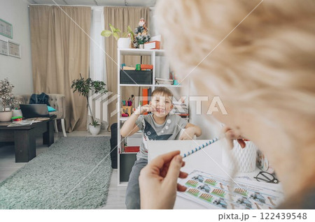 boy smiling and look at camera with speech therapy exercises in a bright educational office with a female therapist, concept of childhood development, education 122439548