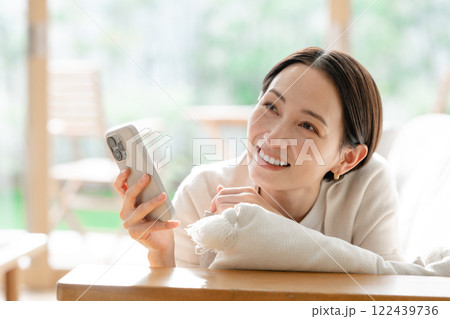 ソファで横になってスマホを見る女性 ソファで横になってスマホを見る女性 122439736