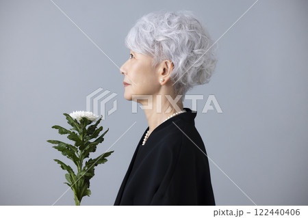 喪服を着て菊の花を持っているシニア女性 喪服を着て菊の花を持っているシニア女性 122440406